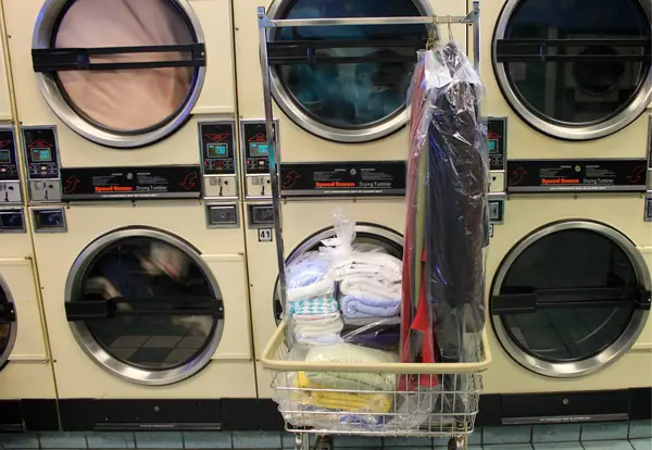 Cart of freshly folded laundry in plastic bags, with shirts on hangers, ready for pickup